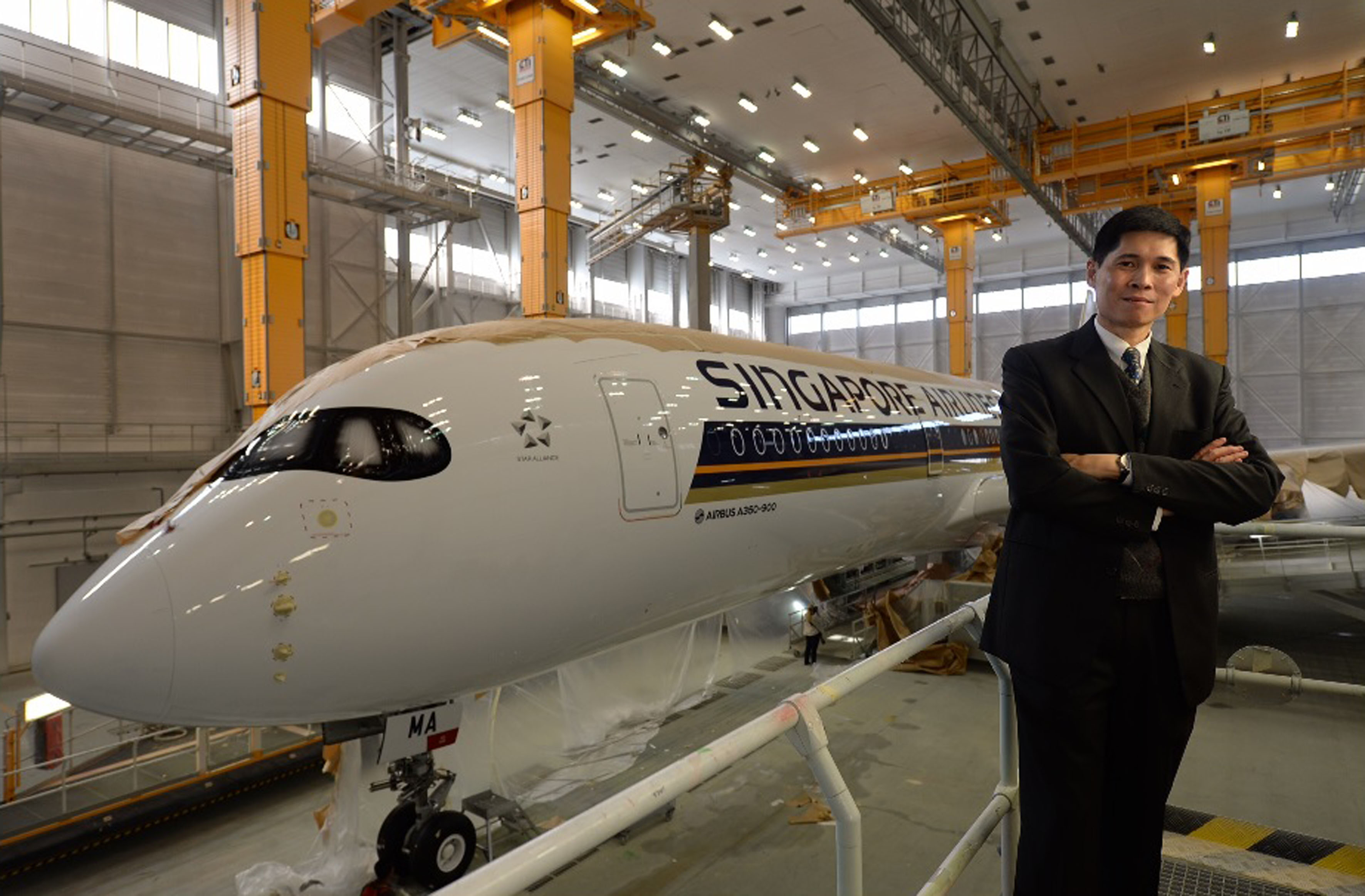 Mr Tan Pee Teck, with SIA's new A-350, which is being painted in the carrier's colours at the Airbus paint shop in Toulouse, France, yesterday. The airline has 63 A-350s on order. After the first jet arrives in January, another 10 are scheduled to be