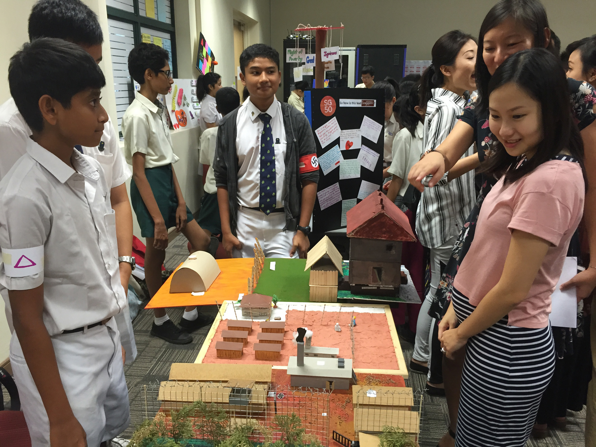Secondary 2 students Mark Joshua John (in cardigan), Pranav Ghosh (far left) and Kenji Ng (partially hidden) showing visitors their model of the Auschwitz concentration camp at the recent National Schools Literature Festival.