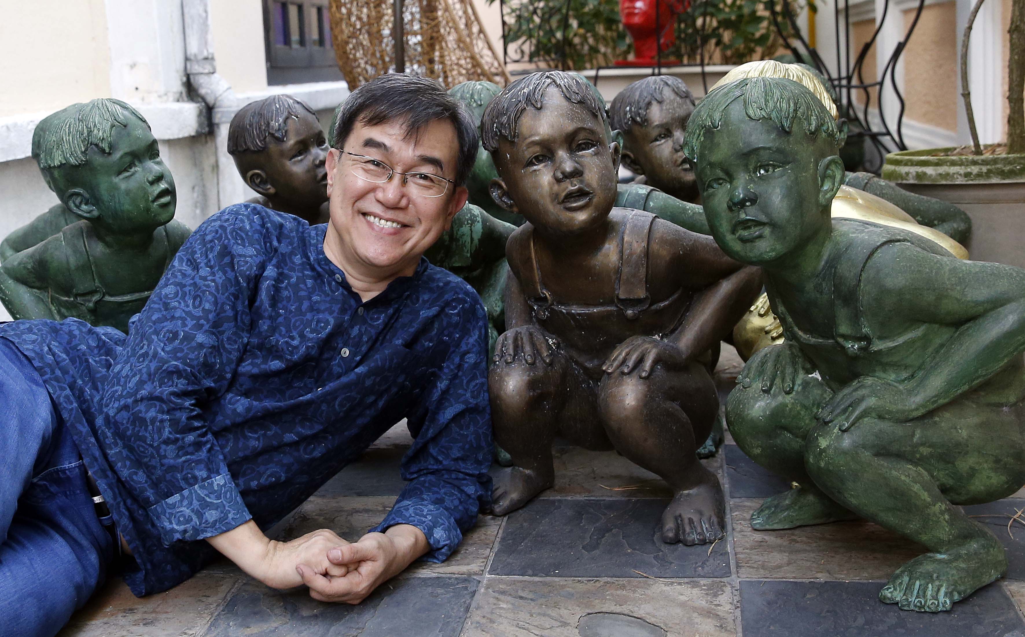 Mr Sim, with the sculptures of a boy squatting down, in his Katong home. He said the boy represents his three-year-old self having to do his business in the open in the kampung he used to live in, adding: "We've come a long way since then."