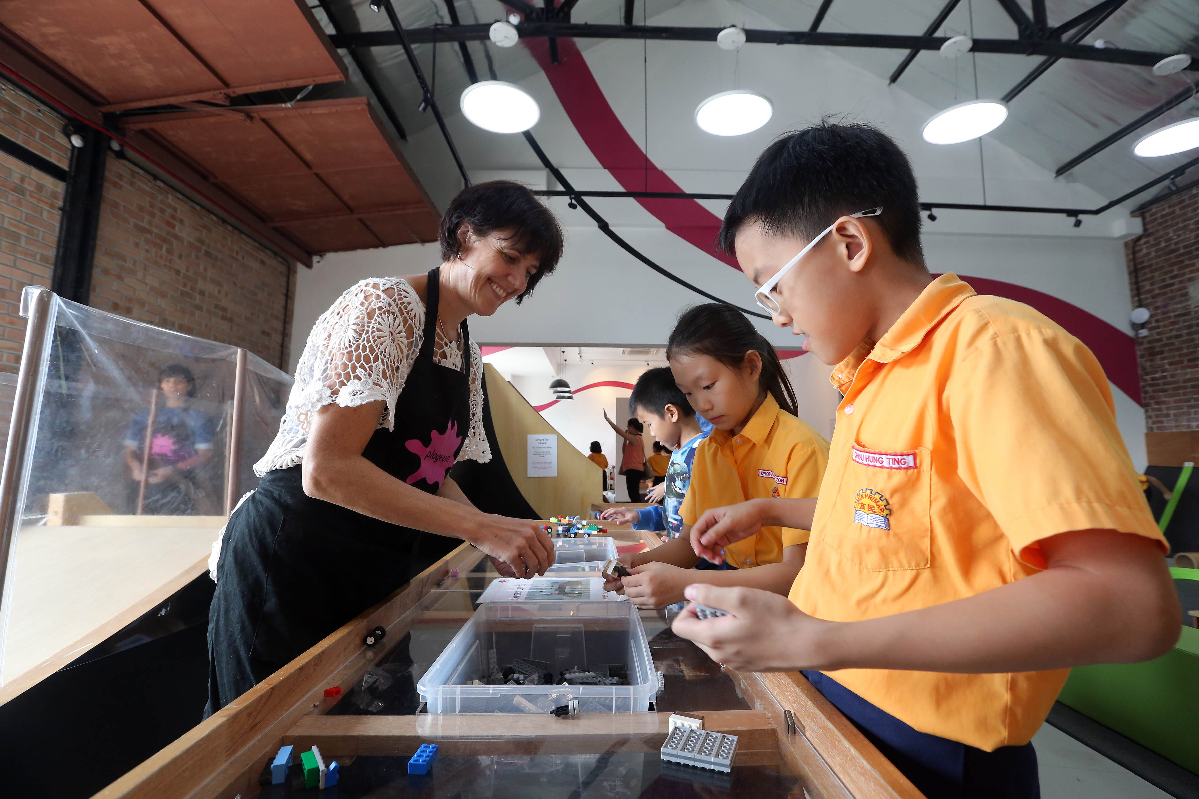 Playeum's executive director Anna Salaman joining Primary 3 pupils from Yumin Primary School in making toy cars using Lego bricks.