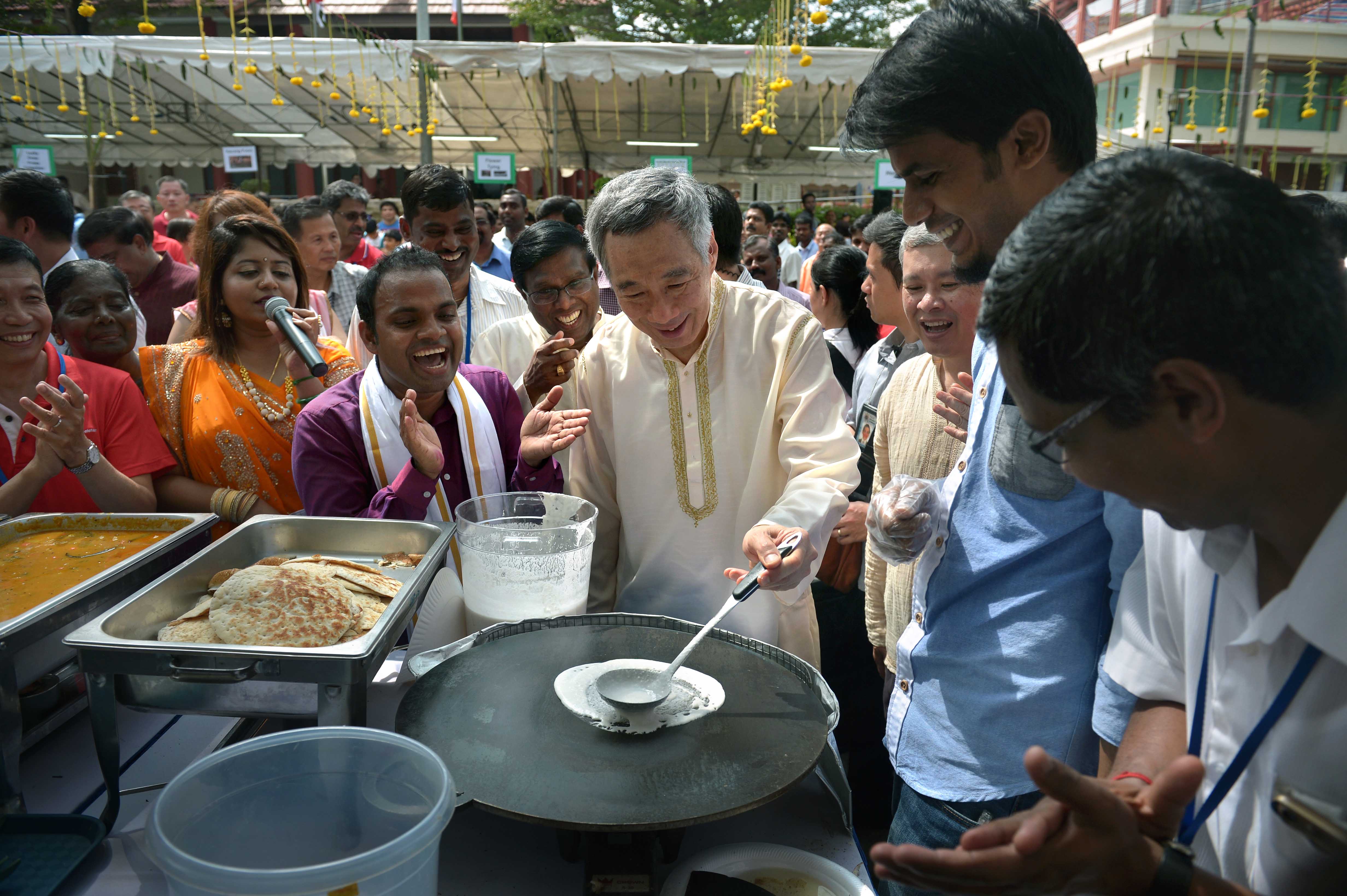 Prime Minister Lee Hsien Loong trying his hand at making Indian snacks like thosai and murukku yesterday at a Pongal celebration at Cheng San Community Club. During the Tamil festival to mark the first harvest of the season, milk, rice and jaggery -