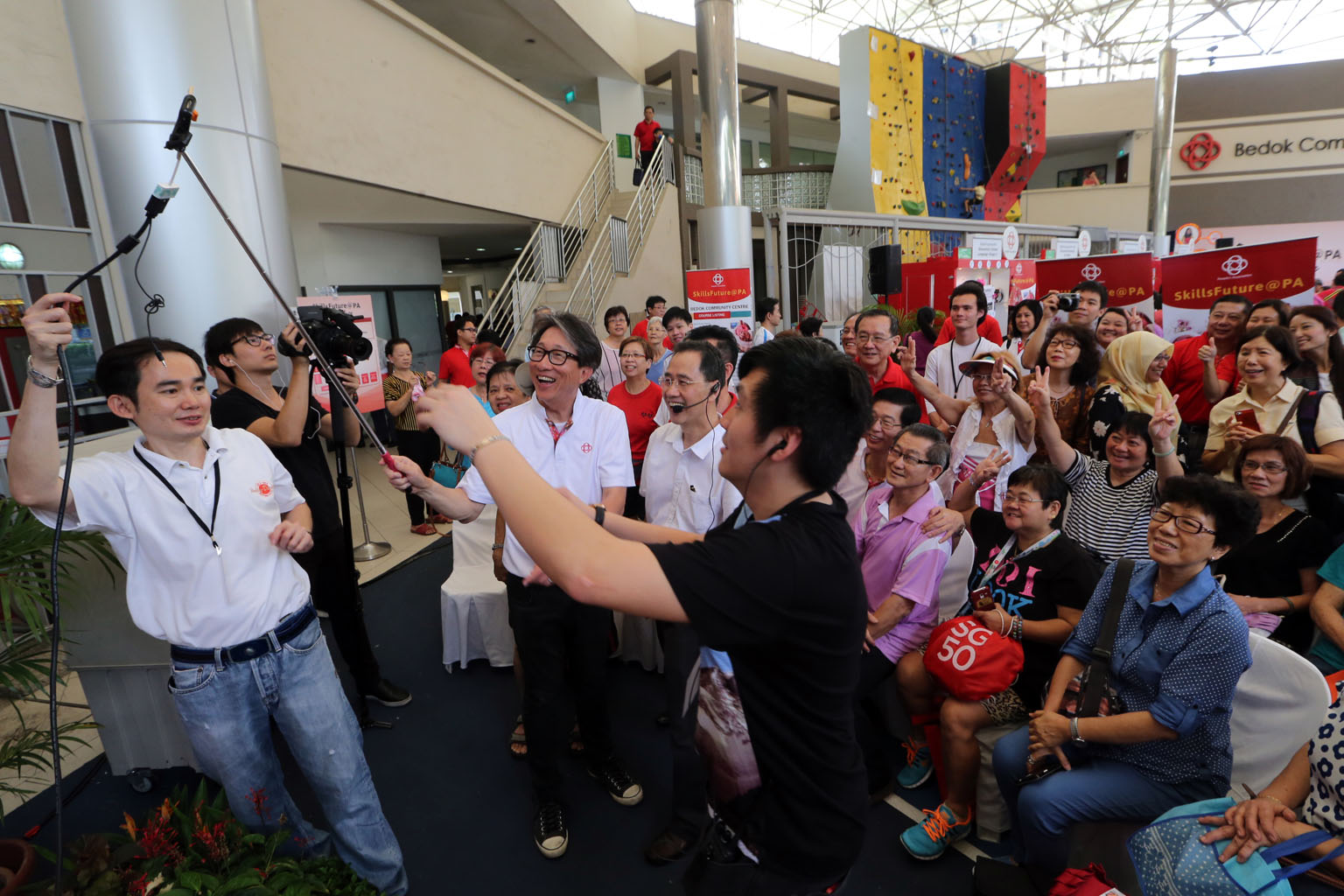 Manpower Minister Lim Swee Say (centre) trying out a selfie stick at the Bedok Community Club event yesterday.