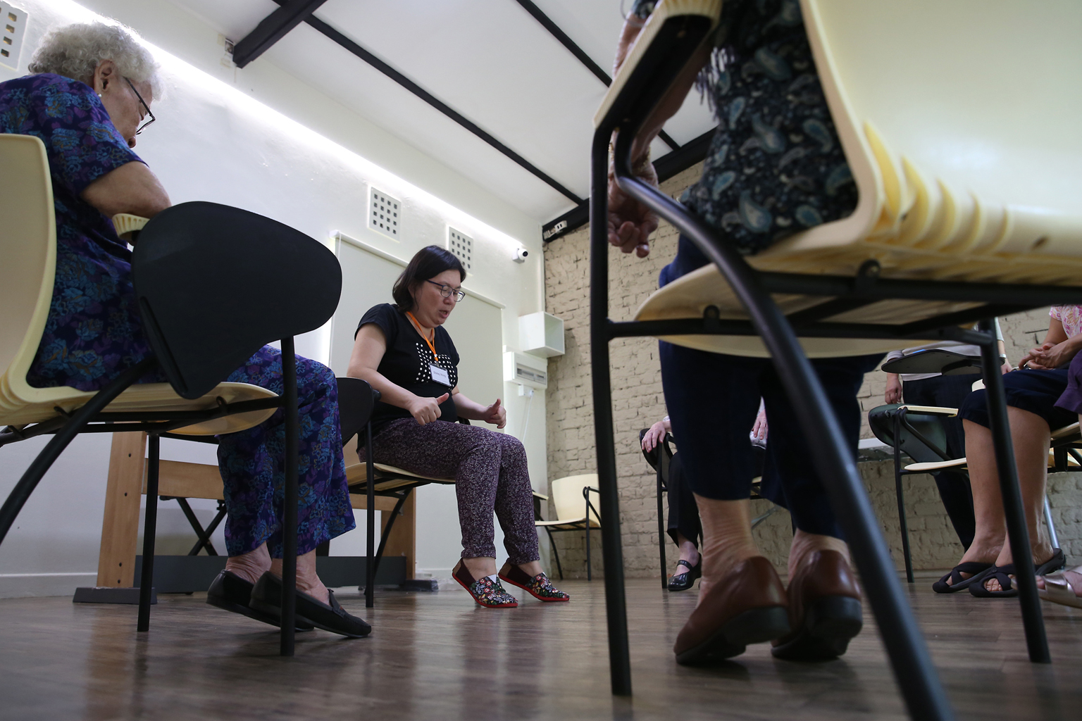 Activity facilitator Shirley Wong engaging dementia patients with light stretching and physical activities at the Montessori for Dementia Care centre. At the privately run centre, clients rise to the challenge of their abilities, said its director, D