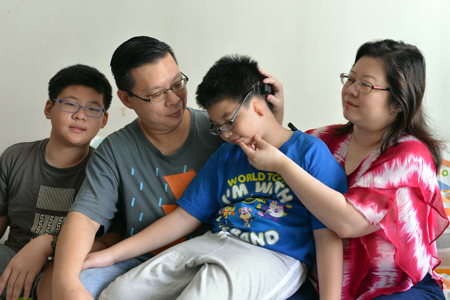 Benjamin (centre) with his parents showing the Baha Attract, a new hearing aid that uses a magnet embedded under the skin instead of a screw to hold the sound processor in place.