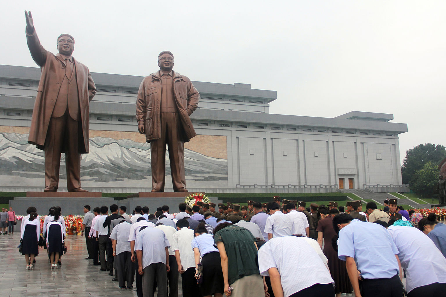 On Victory Day, university students perform mass dances at Kim Il Sung Square (above) while other North Koreans pay their respects at the towering bronze statues of late presidents Kim Il Sung and Kim Jong Il (left). Cycling is a popular way to get a