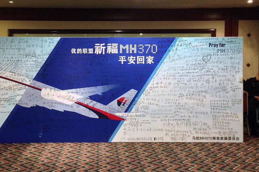 A policeman takes a nap beside a board written with messages for passengers onboard the missing Malaysia Airlines Flight MH370 during a closed meeting held between Malaysian representatives and Chinese relatives of passengers on Flight MH370 at Lido 