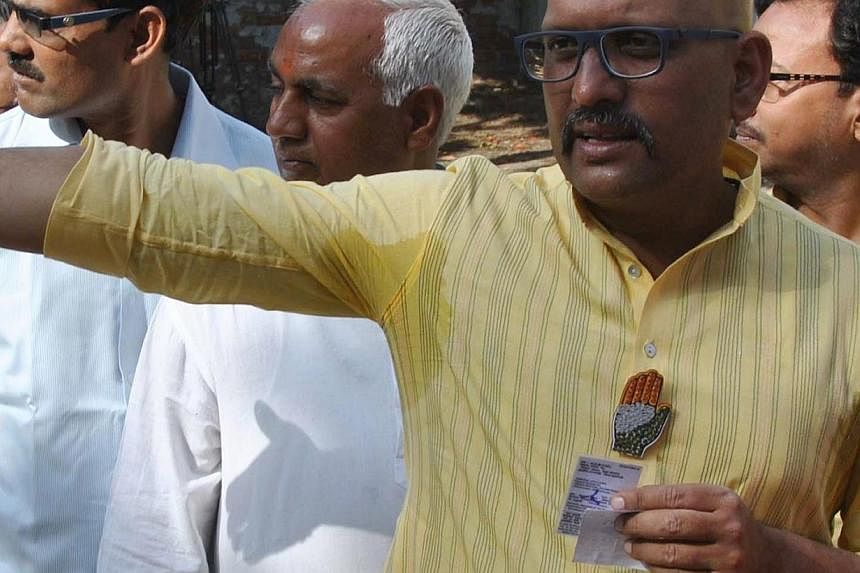 India's Congress party candidate Ajay Rai is pictured wearing a lapel pin bearing his party's logo as he waits in line to vote at the Ramakant Nagar polling station in Varanasi on May 12, 2014. -- PHOTO: AFP