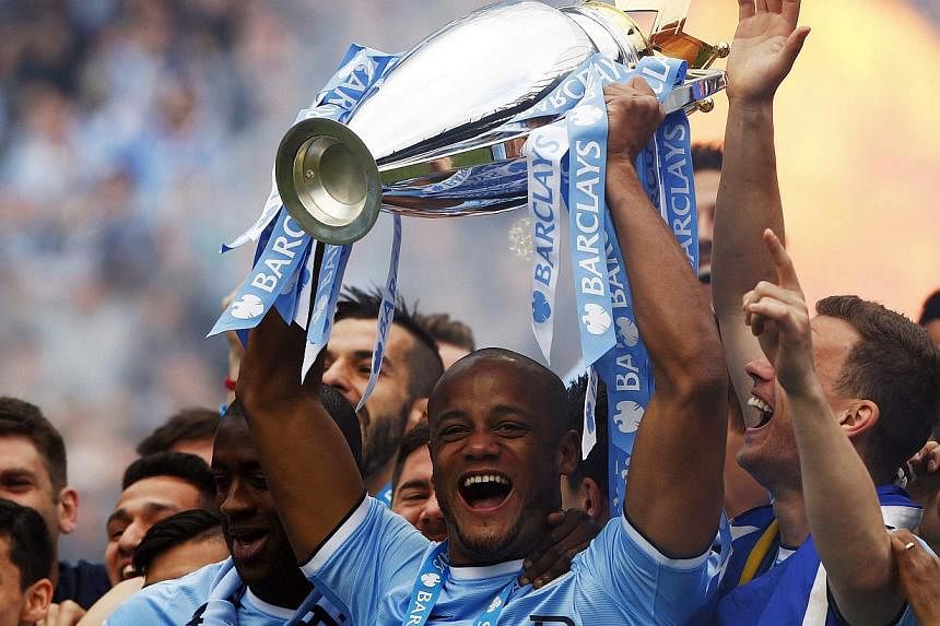 Manchester City's Vincent Kompany celebrates with the English Premier League trophy following their soccer match against West Ham United at the Etihad Stadium in Manchester. -- PHOTO: REUTERS