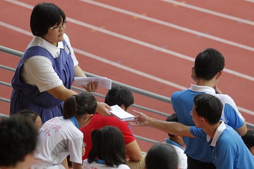 A Secondary School student (left) handing out letters during the national inter-primary school track and field championships held on April 12, 2011, at the Bishan Stadium. -- ST FILE PHOTO:&nbsp;KEVIN LIM