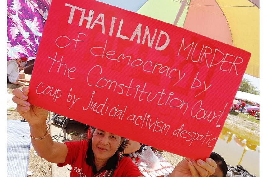 A Thai pro-government Red Shirt protester holds a placard during a rally on the outskirts of Bangkok, Thailand, on May 11, 2014. Six months of political turmoil has created Thailand's biggest ever crisis, the leader of the country's Senate said on Mo
