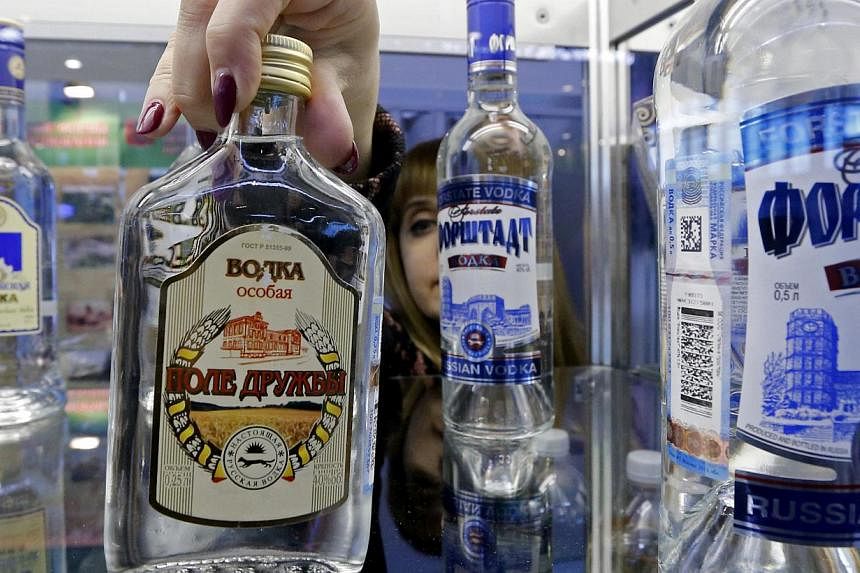 An employee places a bottle of vodka on a counter during the agro-industrial exhibition "Agrorus" in St. Petersburg on April 4, 2014.&nbsp;More than 3 million people died from using alcohol in 2012, for reasons ranging from cancer to violence, the Wo