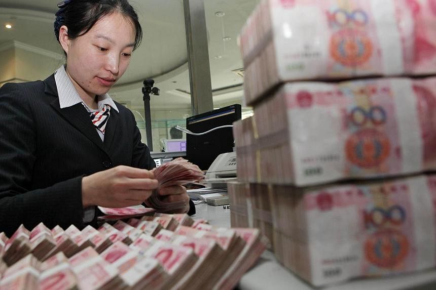 A teller counting notes in a bank in Ganyu county, east China's Jiangsu province. China's yuan will one day compete for a place alongside the mighty dollar as a reserve currency hoarded by central banks, analysts say. -- PHOTO: AFP