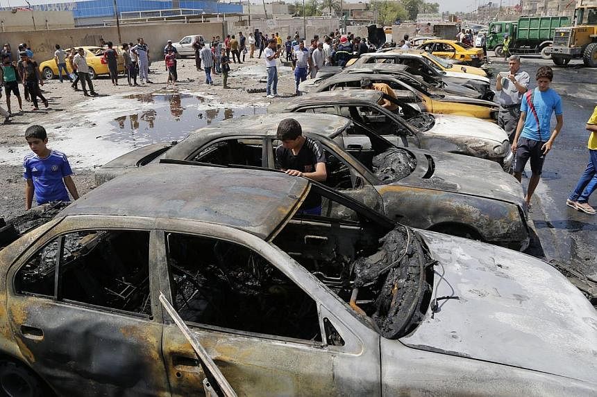 People gather at the site of a car bomb attack in Sadr City district of Baghdad, on May 13, 2014. A spate of rush hour car bombs rocked Shiite-majority areas of Baghdad Tuesday, killing 21 people in the first major series of attacks to hit the Iraqi 