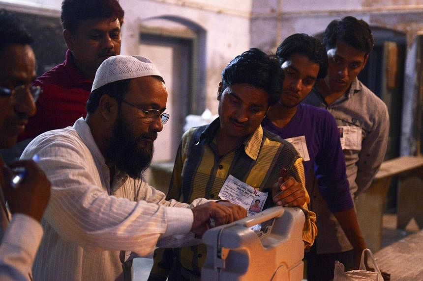 Indian polling station workers take a close look as they seal a box containing an electronic voting machine at the close of polls in the final phase of India's marathon election, in Varanasi on May 12, 2014. A record 551 million voters cast their bal