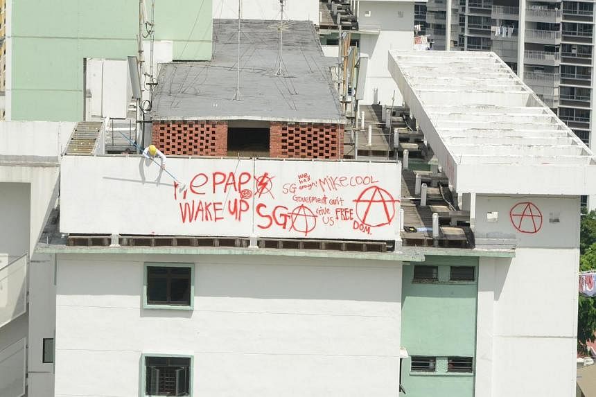 A worker painting over the spray-painted red graffiti across the walls of a rooftop of Block 85A, Lorong 4 Toa Payoh on 7 May 2014. -- PHOTO: SPH