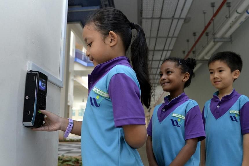West Spring Primary School pupil Hani Arianna Mohd Hafiz scanning her thumbprint while fellow Primary 1 schoolmates Saharnaa Mahendran and Albert Xiong wait in line.