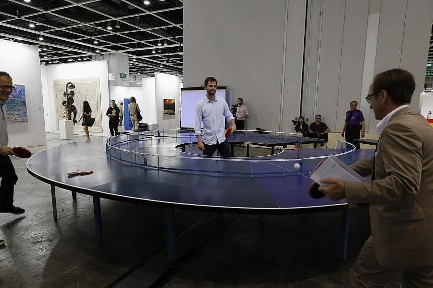 Visitors play table tennis on an artwork titled "Ping Pong Go-Round" by Singapore artist Lee Wen during the preview of Art Basel in Hong Kong on May 14, 2014. -- PHOTO: REUTERS