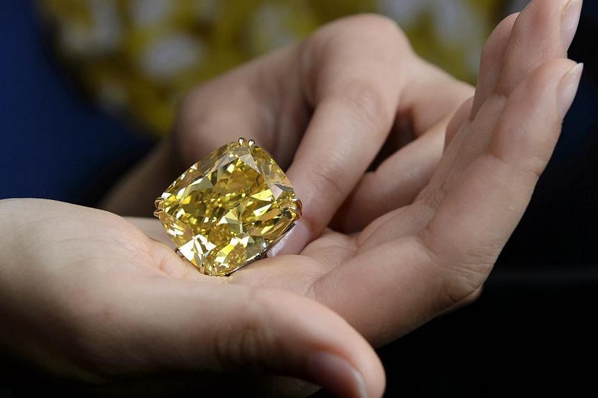 A Sotheby's employee shows The Graff Vivid Yellow at 100.09 carats, one of the rarest yellow diamonds of its size, during a press preview at the Sotheby's, in Geneva, Switzerland, on May 7, 2014. A 100-carat yellow diamond has sold for 14.5 million S