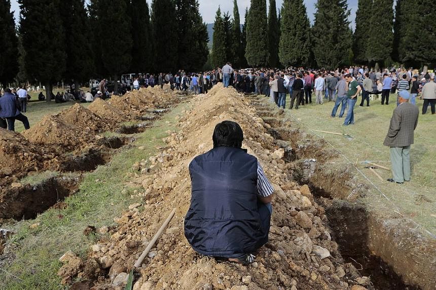 A man sits near graves during the funeral of a miner who died in a fire at a coal mine, at a cemetery in Soma, a district in Turkey's western province of Manisa on May 14, 2014. -- PHOTO: REUTERS