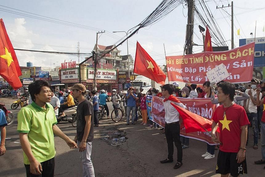 Workers wave Vietnamese national flags during a protest at an industrial zone in Binh Duong province on May 14, 2014. -- PHOTO: REUTERS