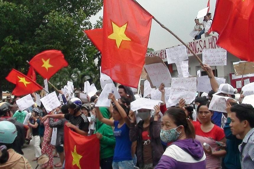 Protesters wave flags and hold placards on a street outside a factory building in Binh Duong on May 14, 2014, as anti-China protesters set more than a dozen factories on fire in Vietnam, according to state media, in an escalating backlash against Bei