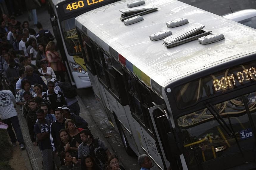 People wait in line to get into a bus during a 48-hour bus strike in Rio de Janeiro on May 14, 2014. The strike renewed concerns about services and public order one month before Rio and 11 other Brazilian cities play host to the upcoming World Cup so