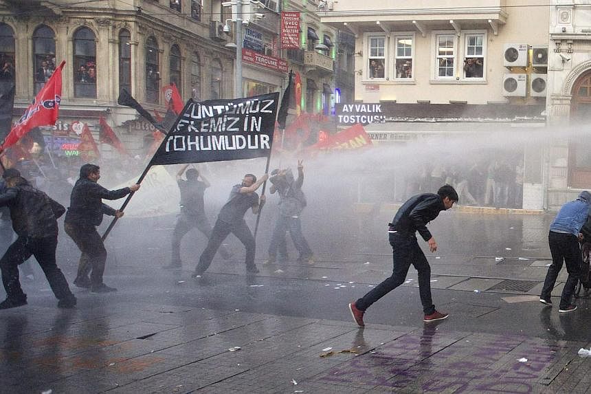 Protesters run away from water canon fired by the riot police during a demonstration blaming the ruling AK Party (AKP) government for the mining disaster in western Turkey, in central Istanbul on May 14, 2014. Turkish police fired tear gas and water 