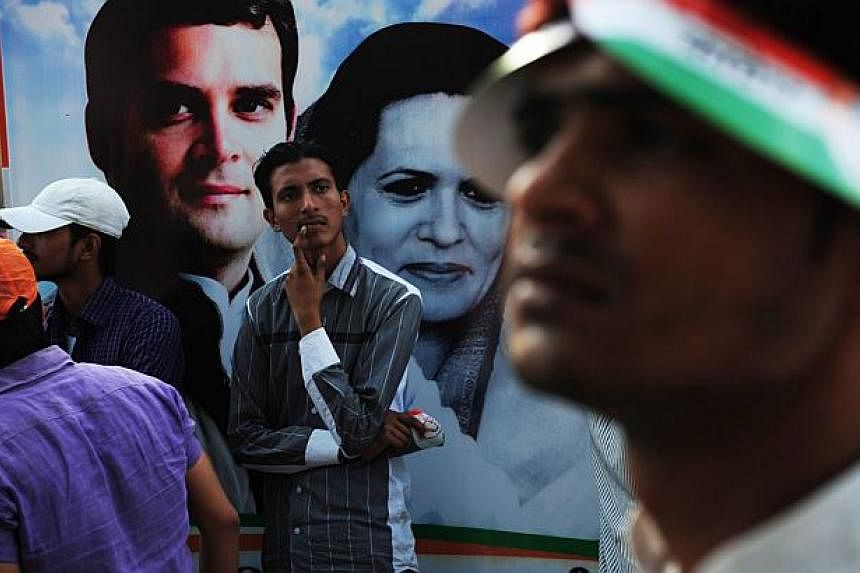 An Indian man stands in front of a poster affixed to a truck showing portraits of Congress Party Vice President Rahul Gandhi (Top L) and Rahul's mother and Congress President Sonia Gandhi (C) during the final day of campaigning in the Indian election