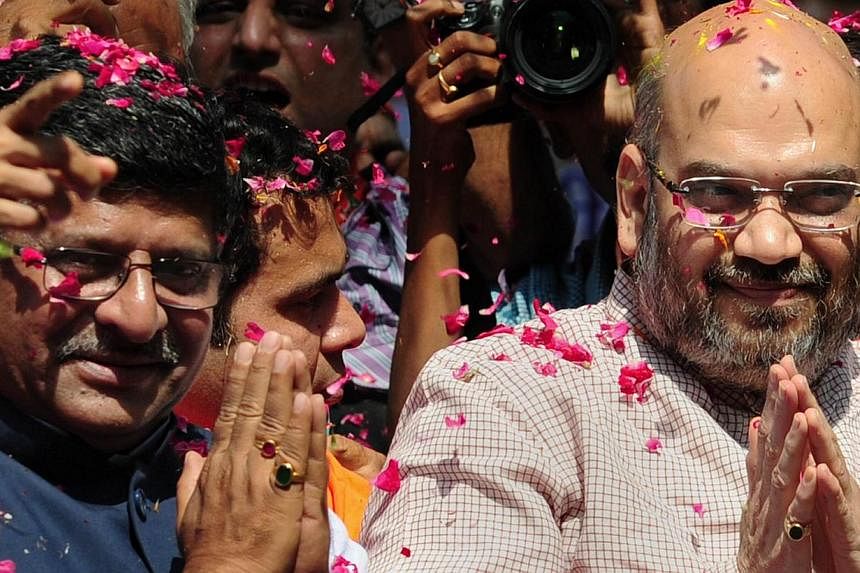 Senior Bharatiya Janata Party (BJP) leaders Amit Shah (R) and Ravi Shankar Prasad (L) greet supporters as they celebrate victory at their party's headquarters in New Delhi on May 16, 2014. -- PHOTO: AFP