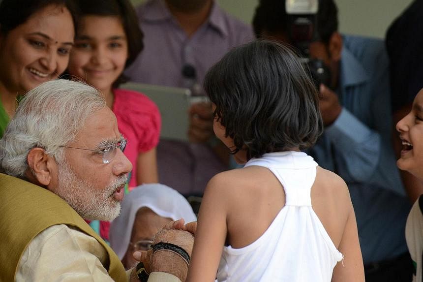 The Chief Minister of India's western Gujarat state and main opposition Bharatiya Janata Party (BJP) prime ministerial candidate, Mr Narendra Modi, interacts with his brother's children at the home of his mother Hira Ba in Gandhinagar, about 23 kms f