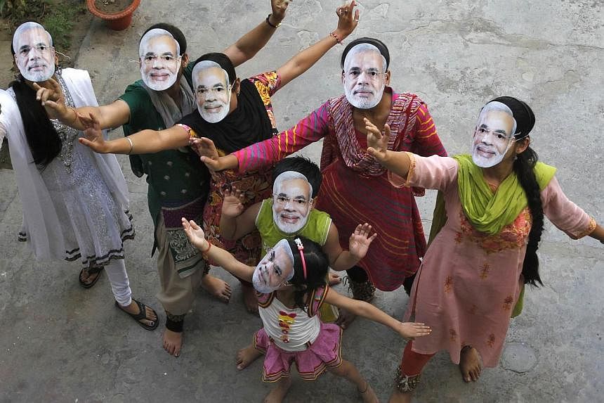 Supporters wearing masks of Hindu nationalist politician Narendra Modi, the prime ministerial candidate for India's main opposition Bharatiya Janata Party (BJP), celebrate after learning of initial poll results in the northern Indian city of Allahaba