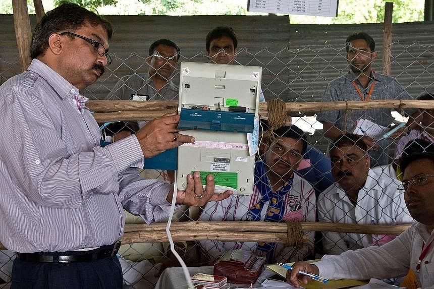 An Indian election official shows the results on an Electronic Voting Machine (EVM) to polling agents at a counting centre in Ghaziabad on May 16, 2014. Early counting trends show a big mandate for the opposition Bharatiya Janata Party (BJP) and Hind