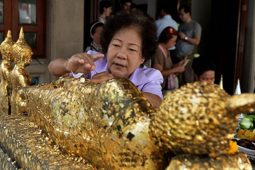 A Thai devotee anoints gold leaves onto a Buddha statue as an offering at Wat Pho, one of the largest and oldest in Bangkok, on February 22, 2014. Residents of&nbsp;Khao Luang district of Loei province, near the northern border with Laos,&nbsp;have f