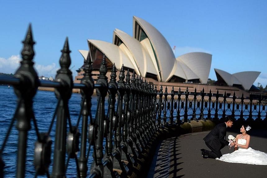 This picture taken on May 13, 2014 shows a bride and groom posing in front of Sydney's iconic land mark Opera House during their photo shoot. -- PHOTO: AFP