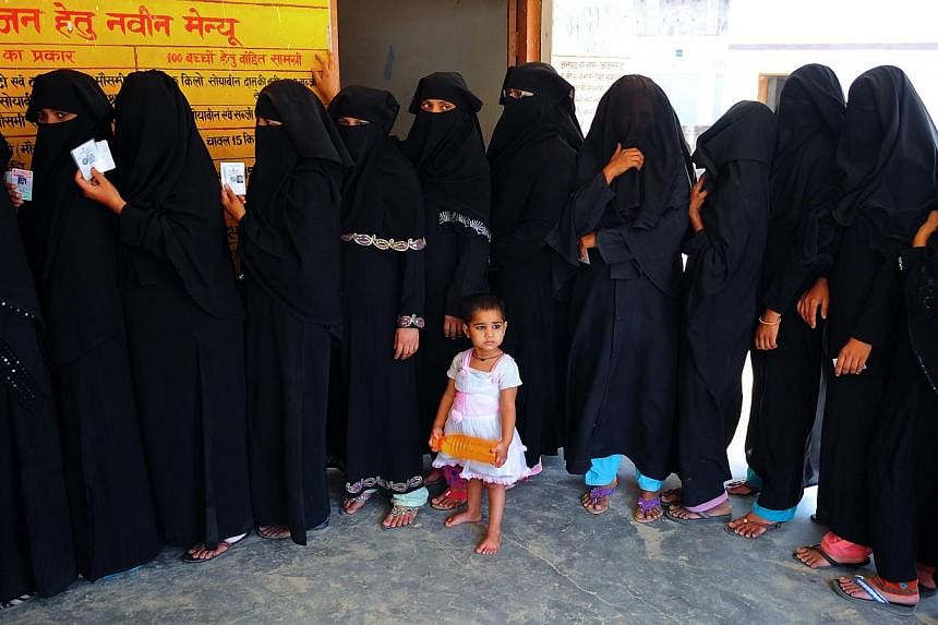 A child looks on as Indian Muslim voters wait in line to cast their ballots at a polling station in Azamgarh, about 275 kms from Lucknow in northern Uttar Pradesh state, &nbsp;on May 12, 2014. He has been pilloried for horrific riots in which hundred