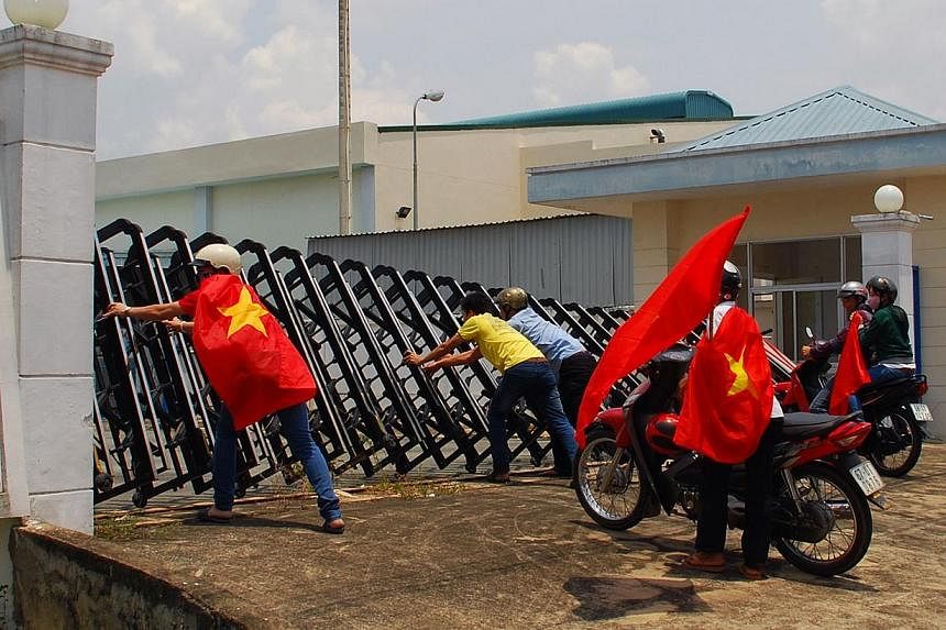 Protesters holding Vietnamese flags attempt to push down the front gate of a factory in Bien Hoa, Dong Nai province, as anti-China demonstrations on May 15 spread to 22 Vietnamese provinces, picture taken on May 14, 2014. Taiwanese workers told of th