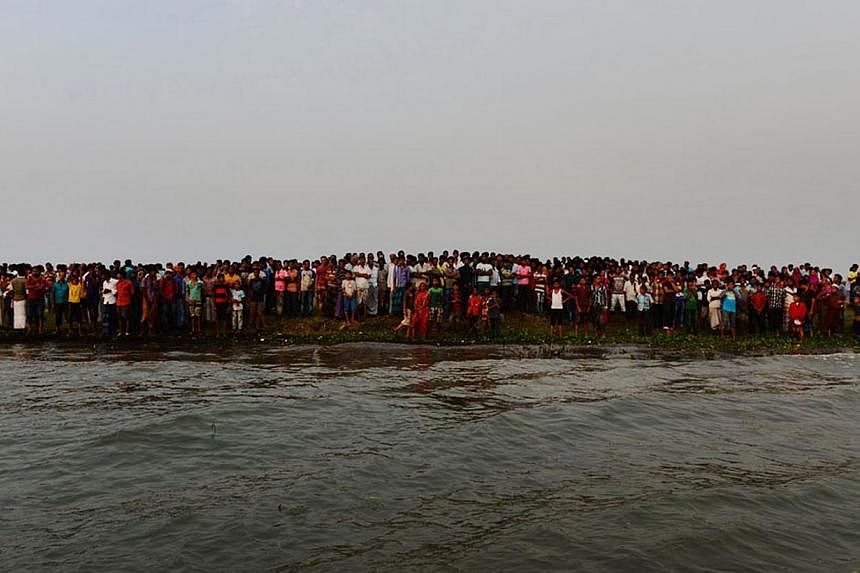 Bangladeshi residents gather near to the site where a ferry capsized and sank in bad weather on the river Meghna in Munshiganj district, some 50km south of the Bangladeshi capital Dhaka on May 15, 2014. A heavily-laden ferry capsized and sank in cent