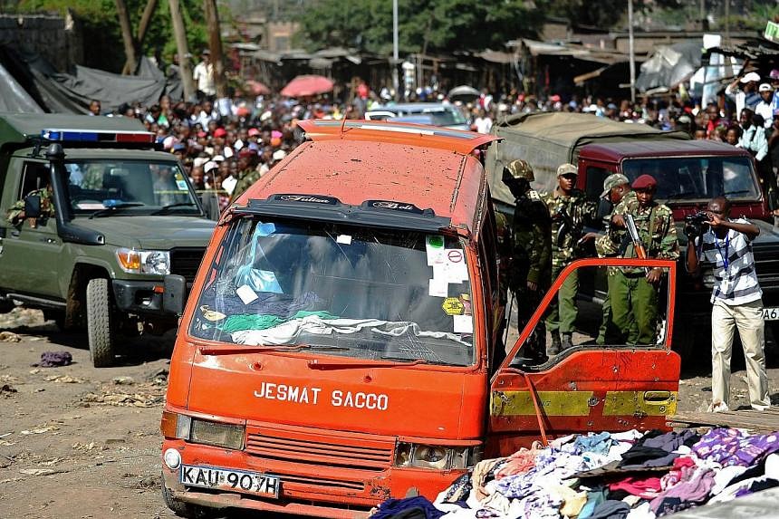 Policemen inspect the scene of an explosion in Gikomba on the outskirts of Nairobi's business district where twin blasts claimed at least ten lives on May 16, 2014. Ten people were killed and over 70 wounded when two bomb attacks in a busy market too