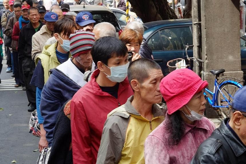 This photo taken on February 26, 2014 shows local homeless people lining up for free food outside the Grace Home Church in Taipei. In recent years the gap in Taiwan between the rich and poor has widened rapidly. -- FILE PHOTO: AFP