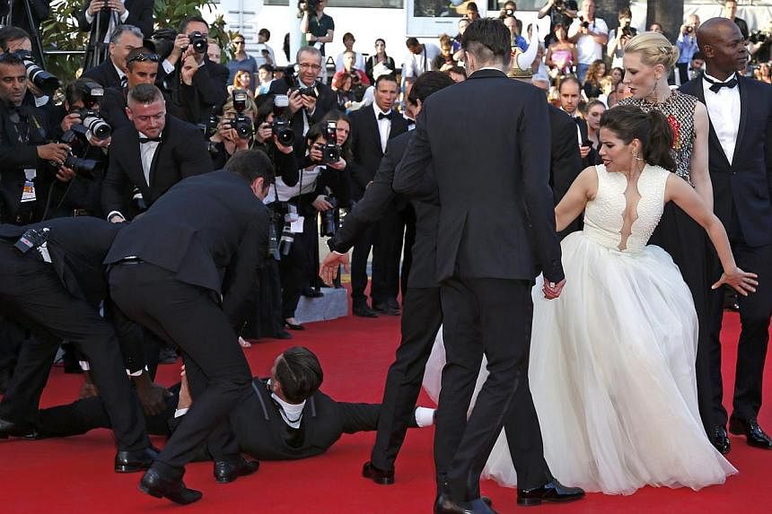 A man is arrested by security as he tries to slip under the dress of actress America Ferrera (third from right) as she poses on the red carpet arriving for the screening of the film How To Train Your Dragon 2 out of competition at the 67th Cannes Fil