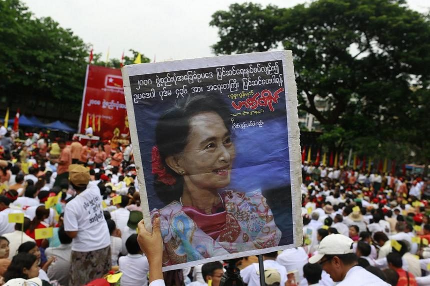 Supporter hold a portrait of Myanmar's pro-democracy leader Aung San Suu Kyi as she delivers a speech calling for the amendment of the 2008 Constitution at a rally in Boseinman Stadium in Yangon, May 17, 2014. -- PHOTO : REUTERS