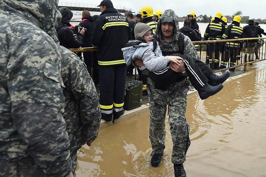 A Serbian emergency response worker carries a child as he and others evacuate people from their flooded homes in the town of Obrenovac, 40km west of Belgrade, on May 16, 2014.&nbsp;Emergency services pulled seven dead bodies from flooded homes in Bos
