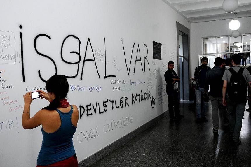 A girl takes a photo of graffiti slogans written by university students from Istanbul Technical University`s Mining Engineering Faculty on May 17, 2014, as part of a protest against the mining disaster that claimed over 300 lives. -- PHOTO: AFP