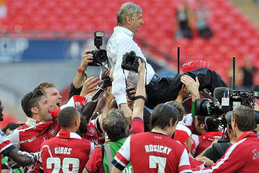 Arsenal players carry their French manager Arsene Wenger as they celebrate after winning the English FA Cup final match against Hull City at Wembly Stadium in London on May 17, 2014. -- PHOTO: AFP
