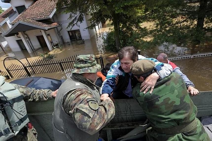A woman is helped by rescuers after being evacuated from her flooded house in the town of Obrenovac, 40 kilometers west of Belgrade&nbsp;on May 17, 2014.&nbsp;&nbsp;-- PHOTO: AFP