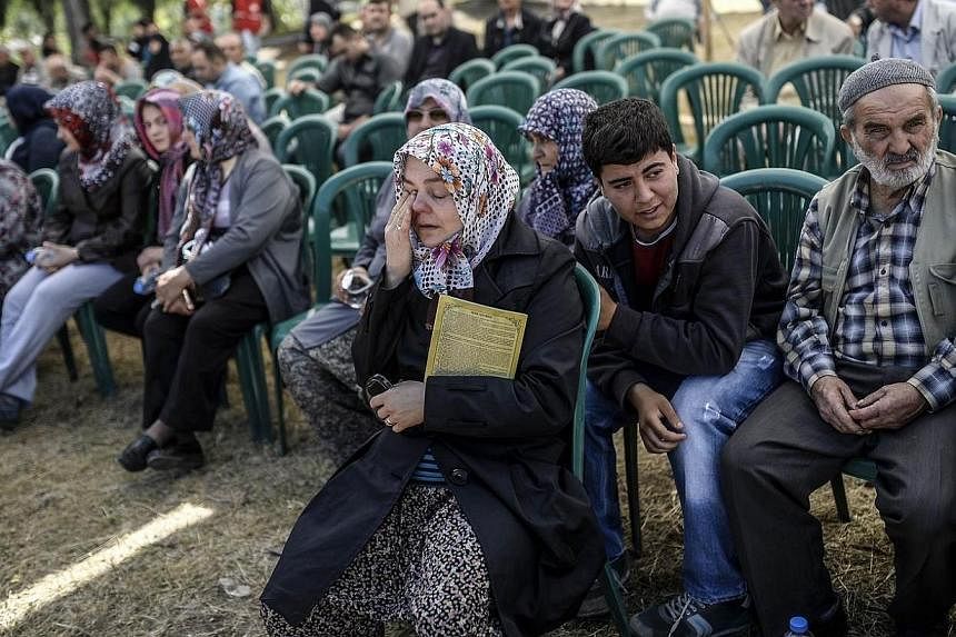 People mourn their relatives at the cemetery where some of the 301 people killed after an explosion and fire in a coal mine were buried on May 18, 2014, at Soma in Manisa.&nbsp;Turkish police on Sunday, May 18, 2014, detained 18 people suspected of n