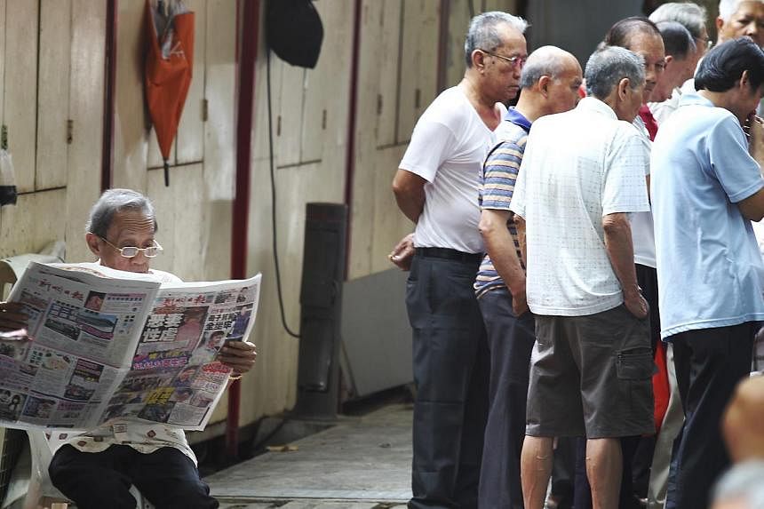 An elderly reading a newspaper while the others watching a game session. -- BT FILE PHOTO: YEN MENG JIN