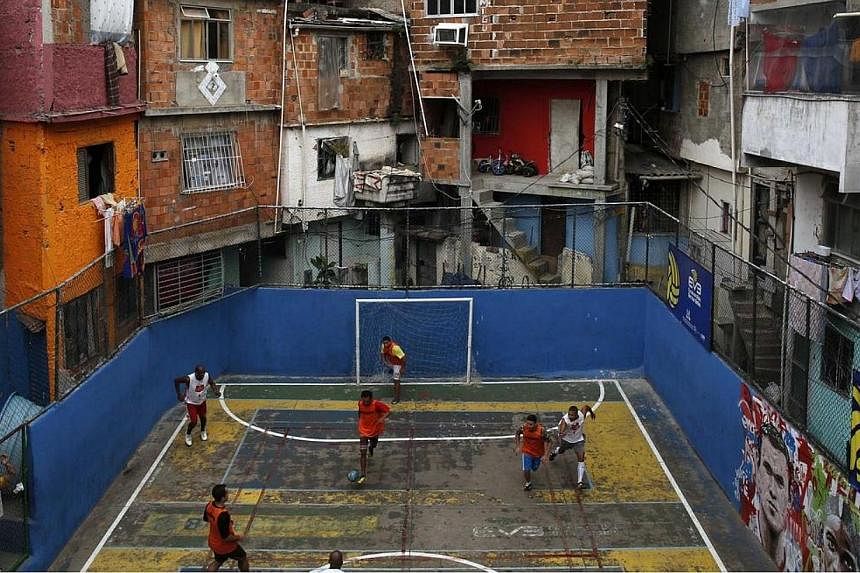 People take part in a soccer match held at the Tavares Bastos slum in Rio de Janeiro on May 18, 2014. The World Cup will be held in 12 cities in Brazil from June 12 till July 13. -- PHOTO: REUTERS