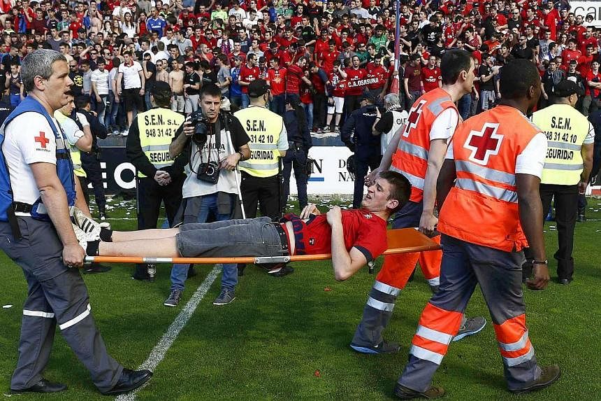 An injured supporter (centre) is stretchered off by medical staff after a railing collapsed during the Spanish Primera Division soccer match between CA Osasuna and Real Betis at the El Sadar stadium in Pamplona, northern Spain, on 18 May 2014. Severa
