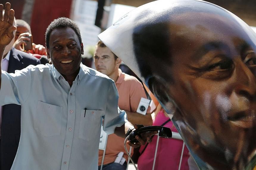 Brazilian football legend Pele waves next to a public telephone booth with an image of his face painted by Brazilian artist Ciprus after he autographed it, during the Call Parade art exhibition in Sao Paulo on May 8, 2014. -- FILE PHOTO: REUTERS